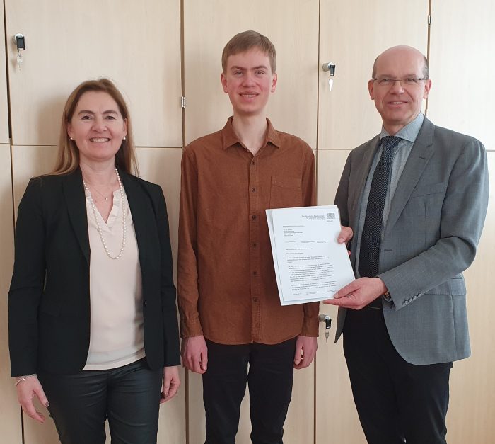 OStD Thomas Bednar, Schulleiter des Maximiliansgymnasiums, und StDin Michaela Weigl, Leitung des Landeswettbewerbs Alte Sprachen in Bayern sowie Fachleitung Latein am Maximiliansgymnasium, gratulieren dem Landessieger Raphael Schneider und überreichen ihm das Anerkennungsschreiben des Bayerischen Staatsministeriums für Unterricht und Kultus.